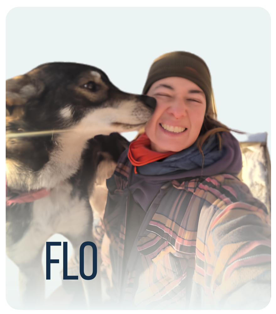 Person smiling while a dog licks their face in a snowy setting.